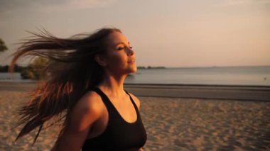 Spor salonundaki kız gün batımının arka planında koşuyor. Sokakta koşan bir kadın. Düşük hareket. Yüksek kalite 4k görüntü