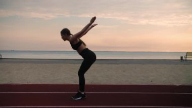 Akrobatik hareketler yapan genç bir kadın. Gün doğumunda sahilde antrenman yapan bir kız. Çocuk parkında ters takla atıyor. Yüksek kalite 4k görüntü