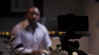 Afrikalı bir adam uzaktan e-öğrenmeyle ilgili konuşmak için akıllı telefonla video blogu yayınlıyor. Blogcu etkileyicisi masada oturarak çevrimiçi kurs alıyor. Siyahi kişi video dersi veriyor. Yüksek kalite