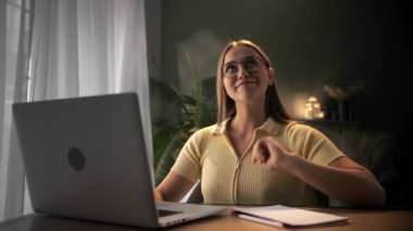 Evdeki masada oturup not defteri kullanarak internetten öğrenme fikri olan bir kadın. Uzaktan eğitim için dizüstü bilgisayar kullanan genç sarışın kız. Uzaktan kumandalı kadın işi. Yüksek kalite 4k