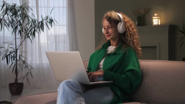 Mulher Usando Fones Ouvido Gosta Ouvir Música Sentada Sofá Casa — Vídeo de Stock