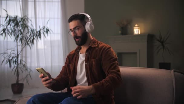 Jovem Celebração Sucesso Usando Smartphone Siting Couch Bearded Cara Usar — Vídeo de Stock