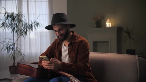 Молодой Человек Празднования Успеха Помощью Смартфона Сидя Couch Bearded Парень — стоковое видео