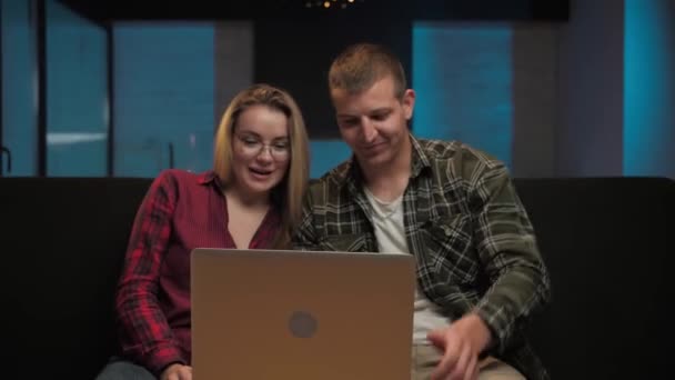 男性と女性は 家庭内のソファに座ってビデオ通話を行います コンピュータ上のWebカメラに話す男と女 高品質4K映像 — ストック動画