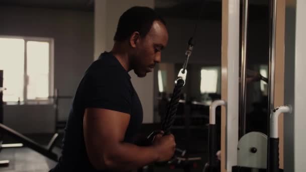 ジムでの黒人男性のワークアウトは トリップのための演習を行う アフリカ系アメリカ人のボディビルダーは クロスオーバー屋内で彼の腕を拡張します 高品質4K映像 — ストック動画