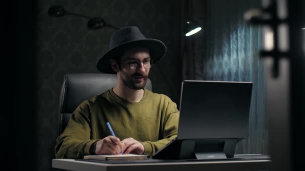 Молодой Бородатый Человек Обучающийся Онлайн Помощью Ноутбука Сидящего Партой Темной — стоковое видео