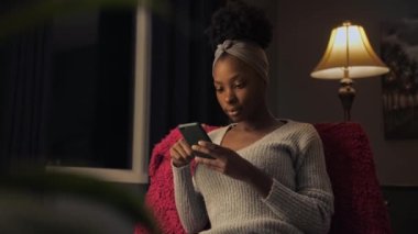 Siyah bir kadın internete girip, telefon kullanıyor. Elinde cep telefonu tutan Afro-Amerikan bir kız. İnternetten alışveriş yapıyor.