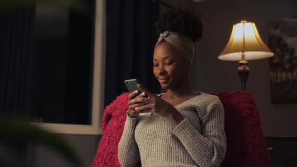 Surprised Black Woman Browsing Internet Using Phone Sitting Dark Home — Stock Video