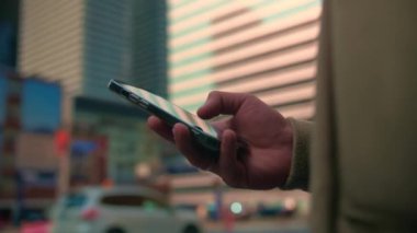 Şehrin arka planında telefon taraması yapan genç bir adama yakın çekim. Adam açık havada akıllı telefonlar yazarak ceket sörf ağı takıyor. Cep telefonu bağımlısı insanlar. Yüksek kalite 4k görüntü
