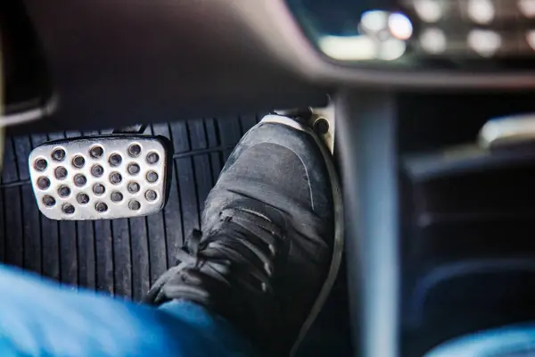 Pair of black sneaker on the floor in a car pressing gas pedal, carefully driving car concept