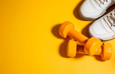 Arka planda gri havluyla iki dambıl ve fotokopi alanı olan bir şişe su.