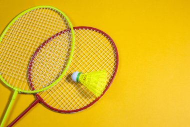 badminton raketleri ve sarı arka planda mekik aleti, spor konsepti