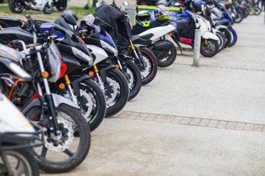 Bir grup motosikletli açık otoparkta arka arkaya park etmiş.