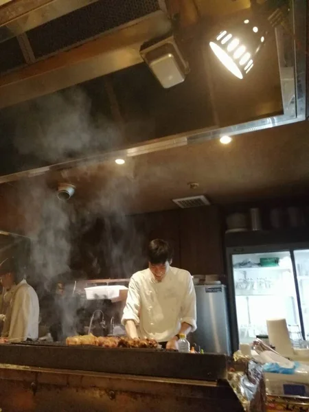 Şef mutfak tezgahında suşi pişiriyor, yemek yapıyor.