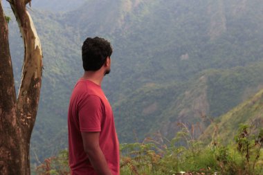  A man contemplating the beauty of Kodaikanal mountains depth standing from another mountain clipart