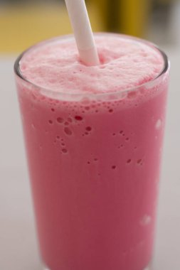 Beyaz bardakta servis edilen renkli ve lezzetli gül sütü. 