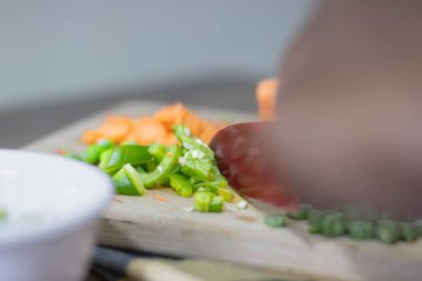 Bıçak tutan ve sebzeleri doğrayan bir adam.