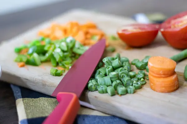 Önlüklü mutfak masası, tahta kesim tahtası, kırmızı Alman bıçağı.