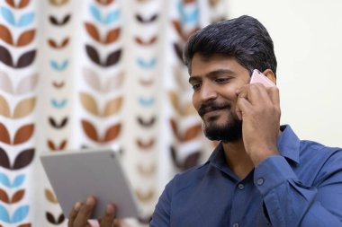 Birden fazla dijital cihaz kullanan mutlu Asyalı Hintli adam, akıllı pho