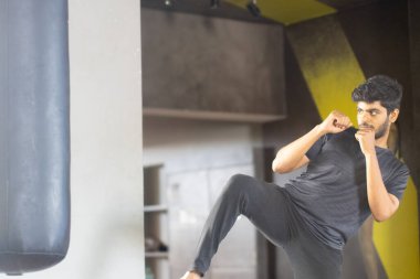 Spor salonunda boks çantasını tekmeleyen yakışıklı adam.