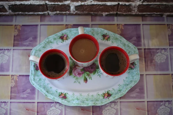 Three white cups with coffee, top view, brick wall and colorful table