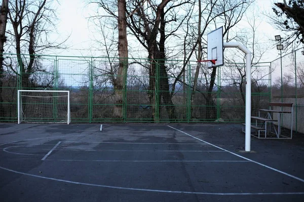 White goal and basket on the field in nature, bench for spectators