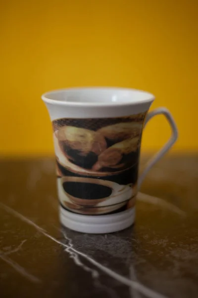 White coffee mug with patterned coffee details, yellow gray background