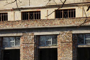 Tuğla sütunları olan eski bir bina, alt tarafında cam olan pencereler ve üst tarafında cam olmayan pencereler.