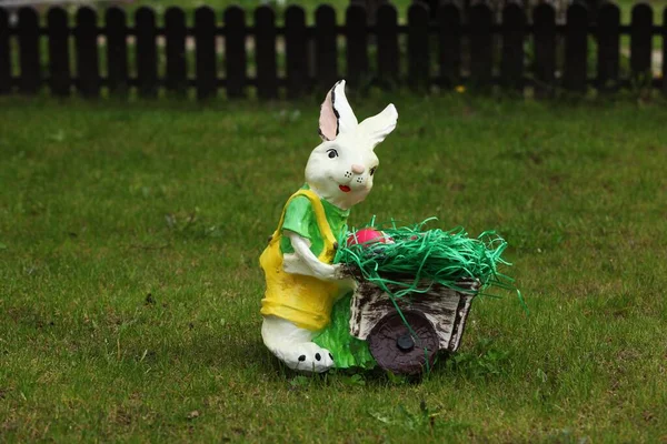 装饰兔子推着推车 后面有栅栏 还有绿草 — 图库照片