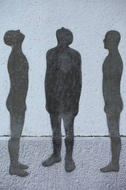 Duvara üç adam çizilmiş, ikisi yukarı bakıyor, biri düz.