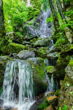 Dağların derinliklerinde büyük kayalarla şelale.