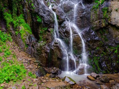 Dağların derinliklerinde büyük kayalarla şelale.
