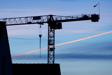 Vinçler ve bina gün batımı bulutları üzerinde yapım aşamasında.