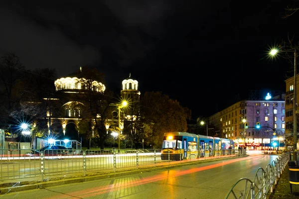 stock image Night scene of tram in traffic at crossing with lighttrail