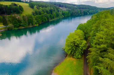 Yeşil yaz ormanı ve mavi nehir manzarası.