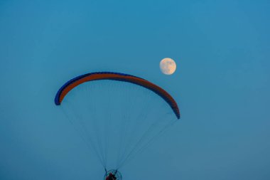 Mavi gökyüzünde dolunay ve hava sporlarıyla paraşütle atlamak