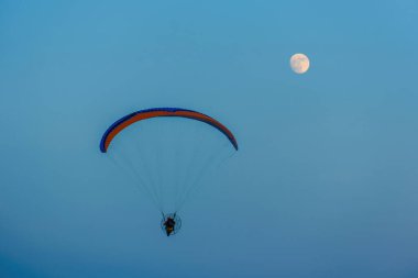 Mavi gökyüzünde dolunay ve hava sporlarıyla paraşütle atlamak