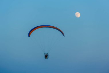 Mavi gökyüzünde dolunay ve hava sporlarıyla paraşütle atlamak