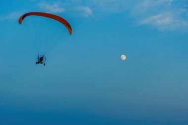Mavi gökyüzünde dolunay ve hava sporlarıyla paraşütle atlamak
