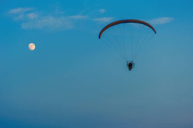 Mavi gökyüzünde dolunay ve hava sporlarıyla paraşütle atlamak