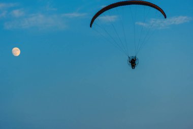 Mavi gökyüzünde dolunay ve hava sporlarıyla paraşütle atlamak