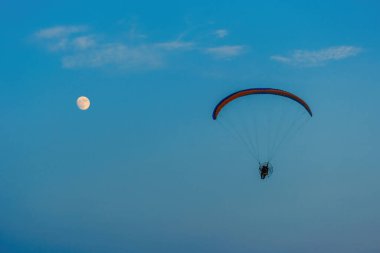 Mavi gökyüzünde dolunay ve hava sporlarıyla paraşütle atlamak