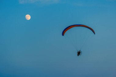 Mavi gökyüzünde dolunay ve hava sporlarıyla paraşütle atlamak