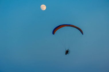 Mavi gökyüzünde dolunay ve hava sporlarıyla paraşütle atlamak