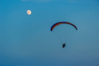 Mavi gökyüzünde dolunay ve hava sporlarıyla paraşütle atlamak
