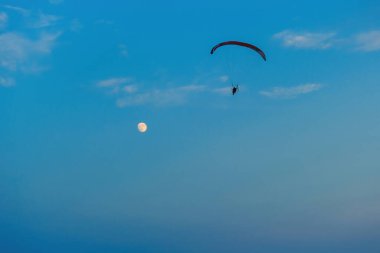Mavi gökyüzünde dolunay ve hava sporlarıyla paraşütle atlamak