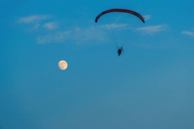 Mavi gökyüzünde dolunay ve hava sporlarıyla paraşütle atlamak