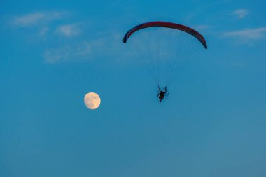 Mavi gökyüzünde dolunay ve hava sporlarıyla paraşütle atlamak