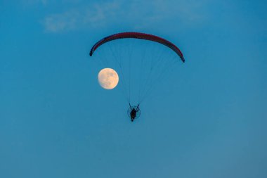 Mavi gökyüzünde dolunay ve hava sporlarıyla paraşütle atlamak