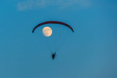 Mavi gökyüzünde dolunay ve hava sporlarıyla paraşütle atlamak
